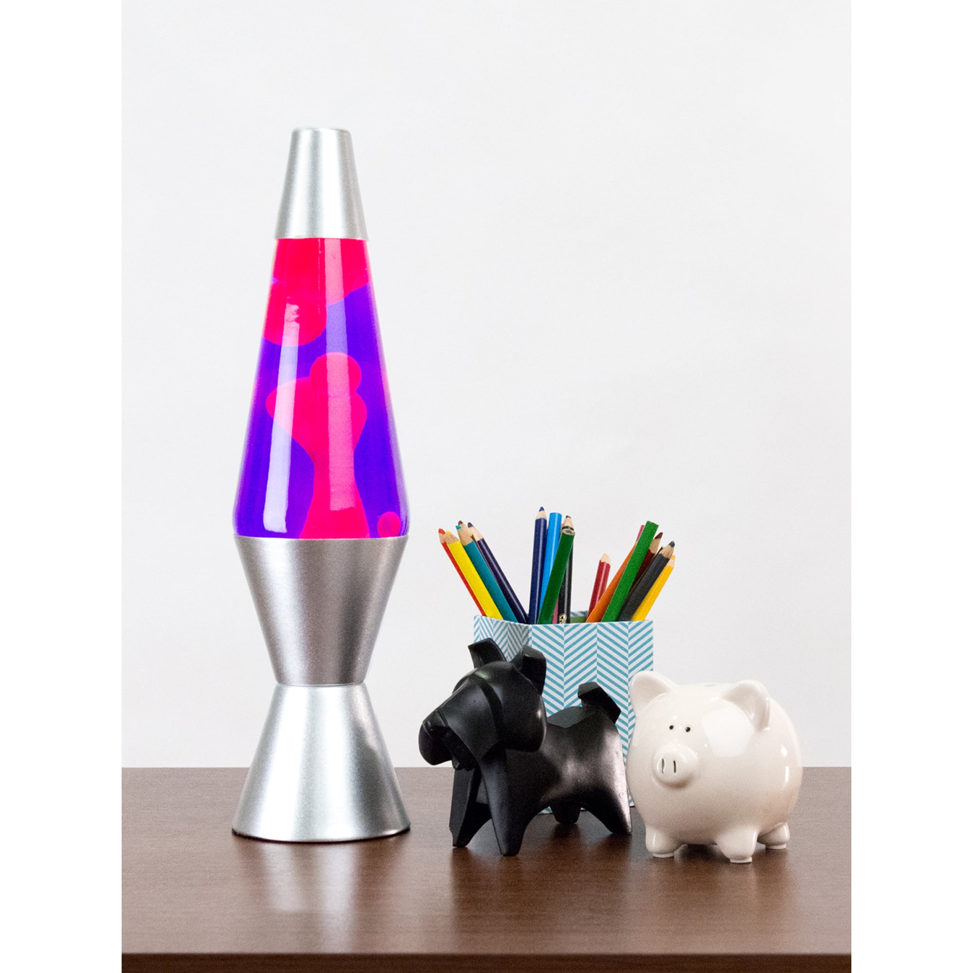 14.5” LAVA® Lamp – Pink/Purple/Silver on table with pencil cup, scotty dog figure, and white piggy bank