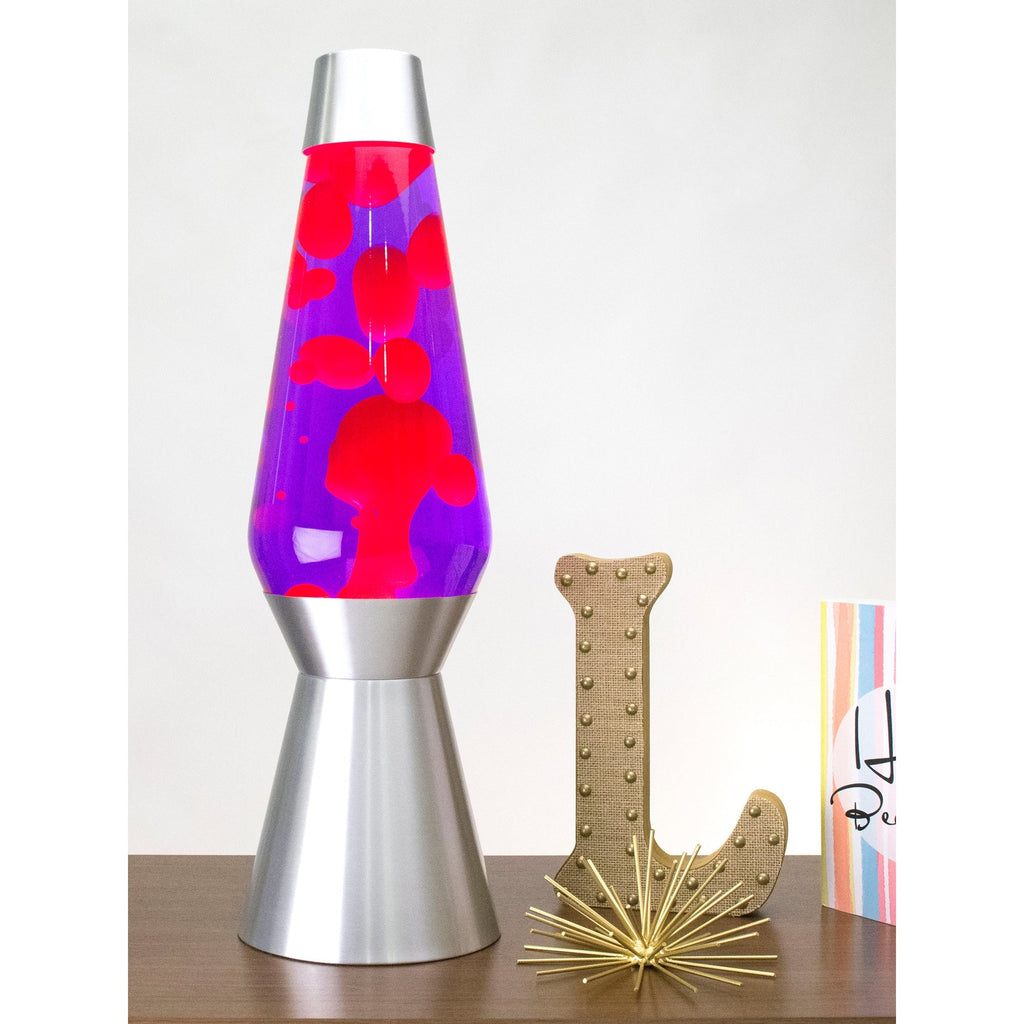 27” LAVA® Lamp Grande – Pink/Purple/Silver on a table with knick knacks